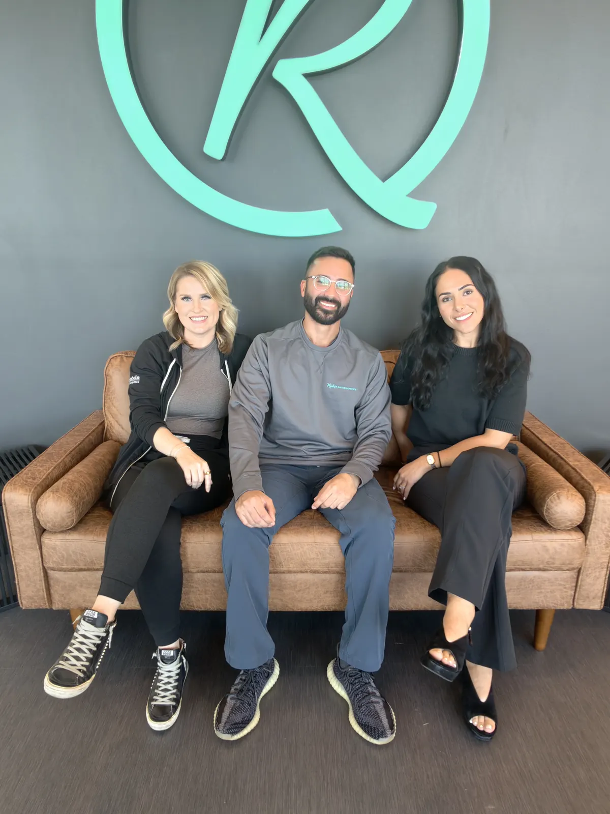 The Rubin Orthodontics team seated together on the leather sofa in reception